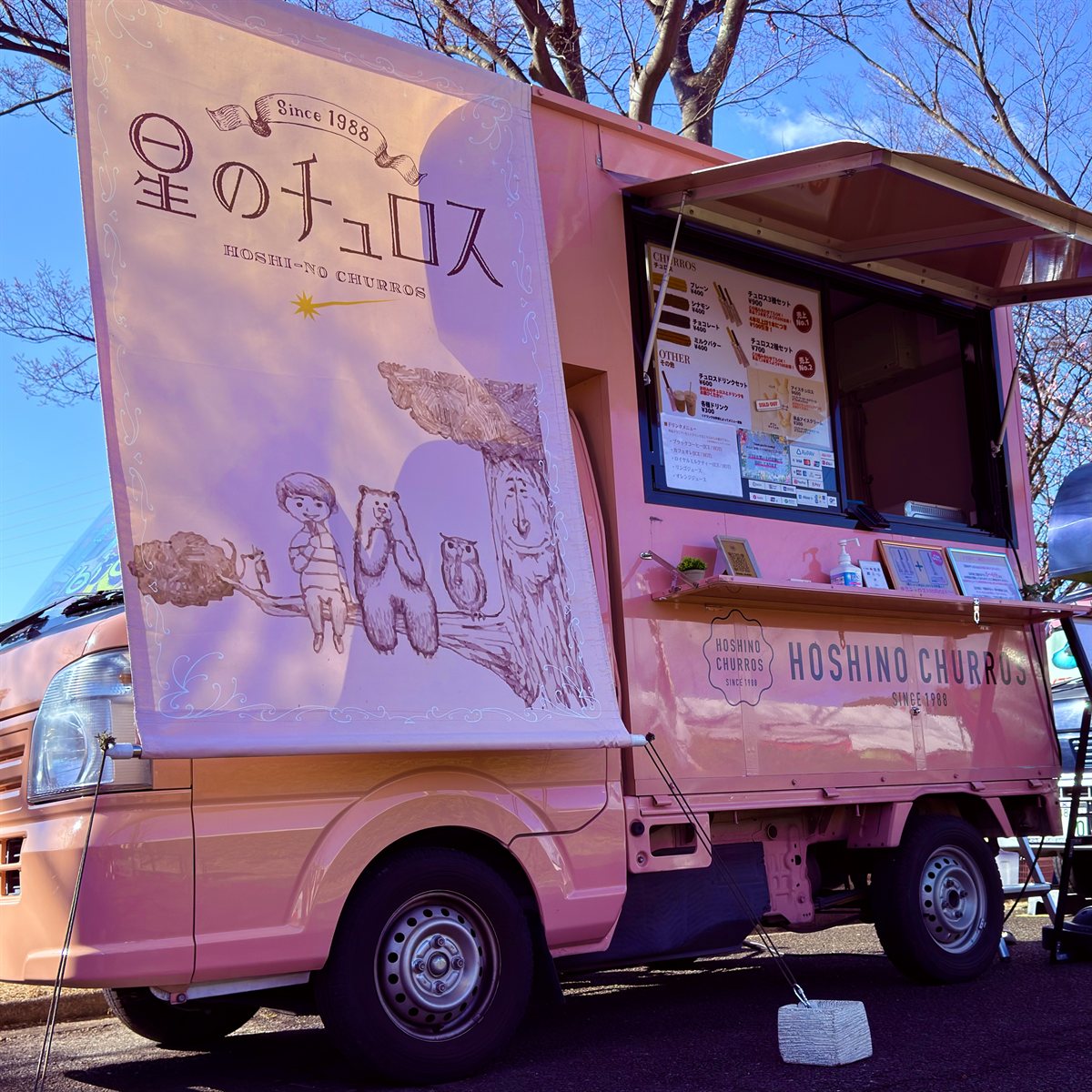 ベージュ背景に白い波形のフレームで囲まれた「HOSHINO CHURROS SINCE 1988」のブランドロゴ