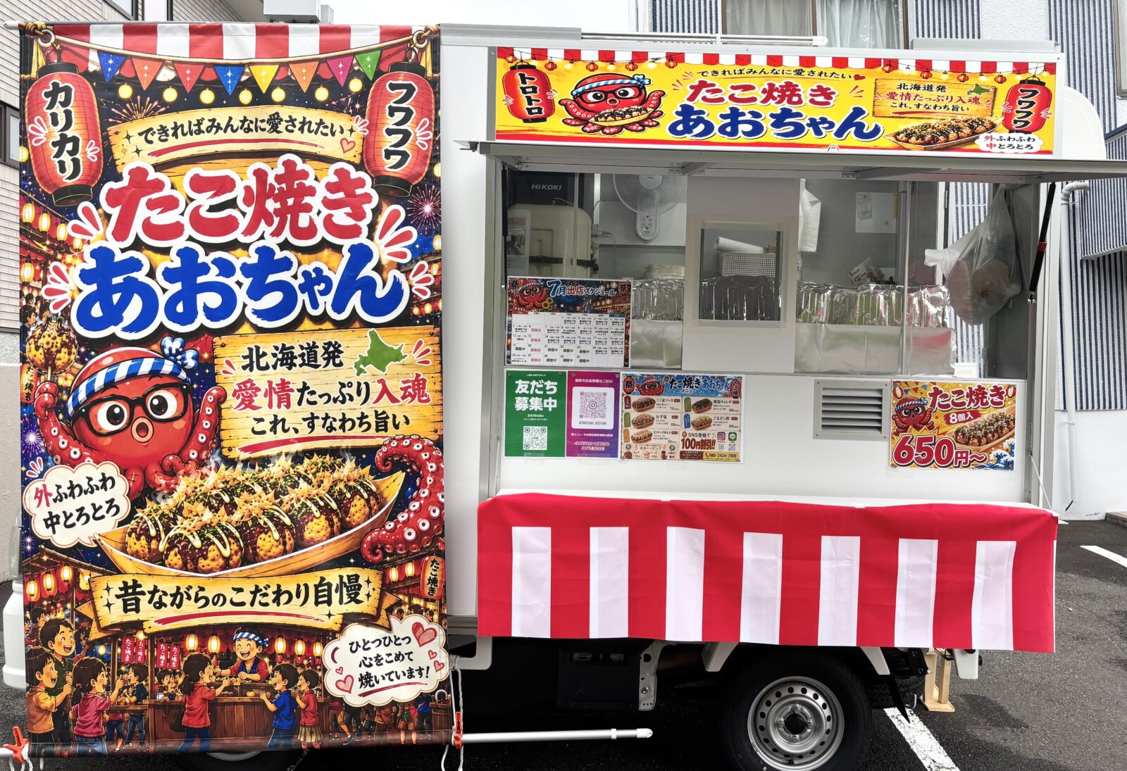 提灯柄の横断幕と赤白の幕をまとった、たこ焼きあおちゃんのキッチンカー